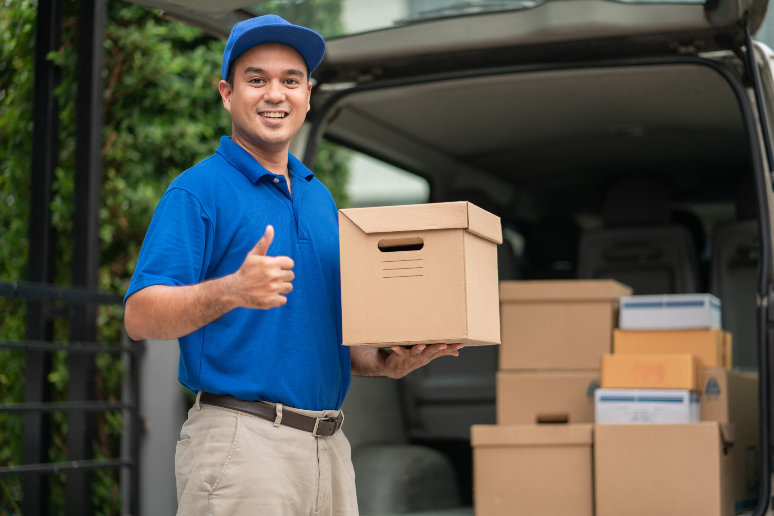 A,Smiling,Young,Asian,Delivery,In,Blue,Uniform,With,Parcel